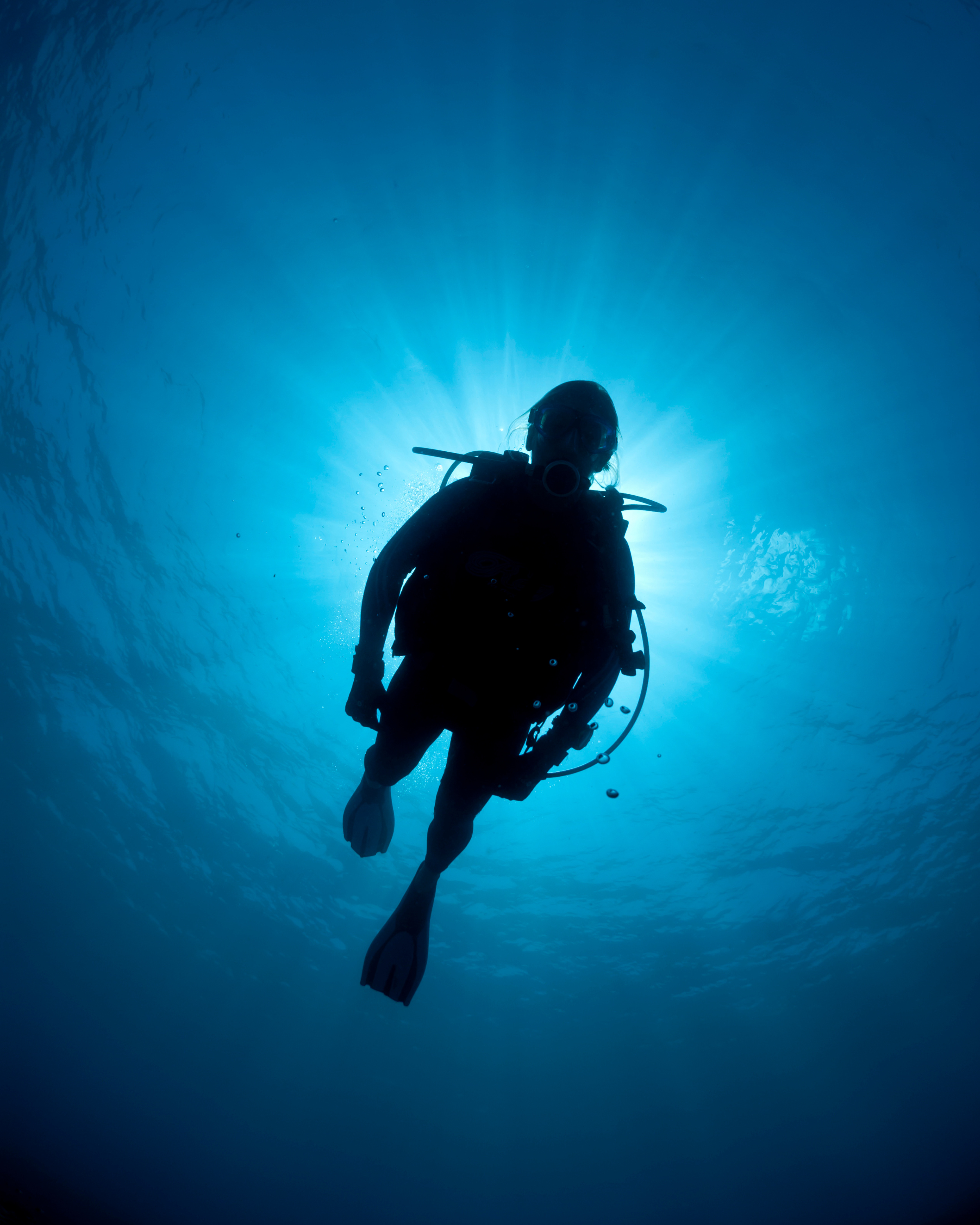 scuba diver underwater silhouette in blue ocean light representing deep sea diving environment.