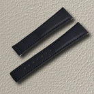 Onyx black sailcloth watch strap with textured surface, tonal stitching, and adjustment holes, displayed on a light beige leather background.