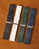 Four watch straps in black, white, green, and blue on a brown background.
