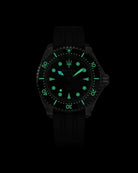 Navanos Ravaro Swiss automatic dive watch in complete darkness with intense green Super-LumiNova lume illuminating the black dial, markers, hands, trident logo, and bezel pip, paired with black FKM rubber strap, 300m water resistance, COSC-certified Soprod P024 movement, studio lume shot on black background.