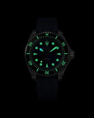 Navanos Ravaro Swiss automatic dive watch in complete darkness with strong green Super-LumiNova lume illuminating the blue sunburst dial, markers, hands, trident logo, and bezel pip, paired with navy blue FKM rubber strap, 300m water resistance, COSC-certified Soprod P024 movement, studio lume shot on black background.