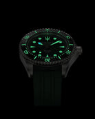 Navanos Ravaro Swiss automatic dive watch in complete darkness lume shot, featuring strong green Super-LumiNova glow on dial, markers, hands, trident logo, and bezel pip, paired with forest green FKM rubber strap, 300m water resistance, COSC-certified Soprod P024 movement, studio shot on black background.