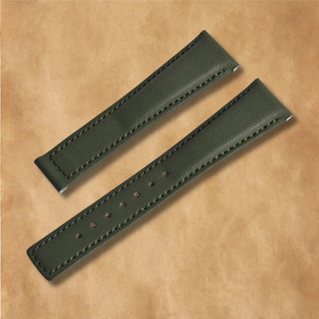 Luxury piton green sailcloth watch strap featuring curved ends, padding, and adjustment holes.